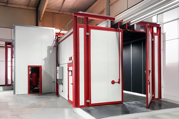 Hier sieht man eine stationäre Strahlanlage mit einem Flügeltor, drei Einfahrschienen an der Decke sowie einem separaten Agregateraum. In diesem befindet sich die gesamte Technik der Strahlanlage. 