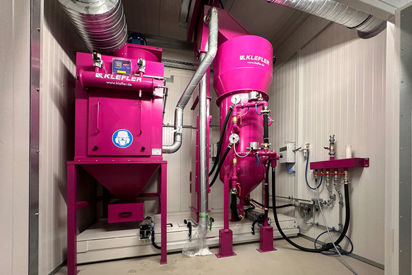 Auf dem Bild ist die kompakte Strahltechnik einer Walzenstrahlanlage zu sehen. Links steht die Patronenfilteranlage und rechts der Doppelstrahlkessel. 